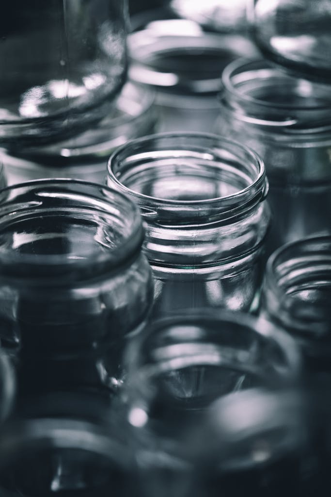 A detailed black and white close-up of several empty glass jars arranged closely.