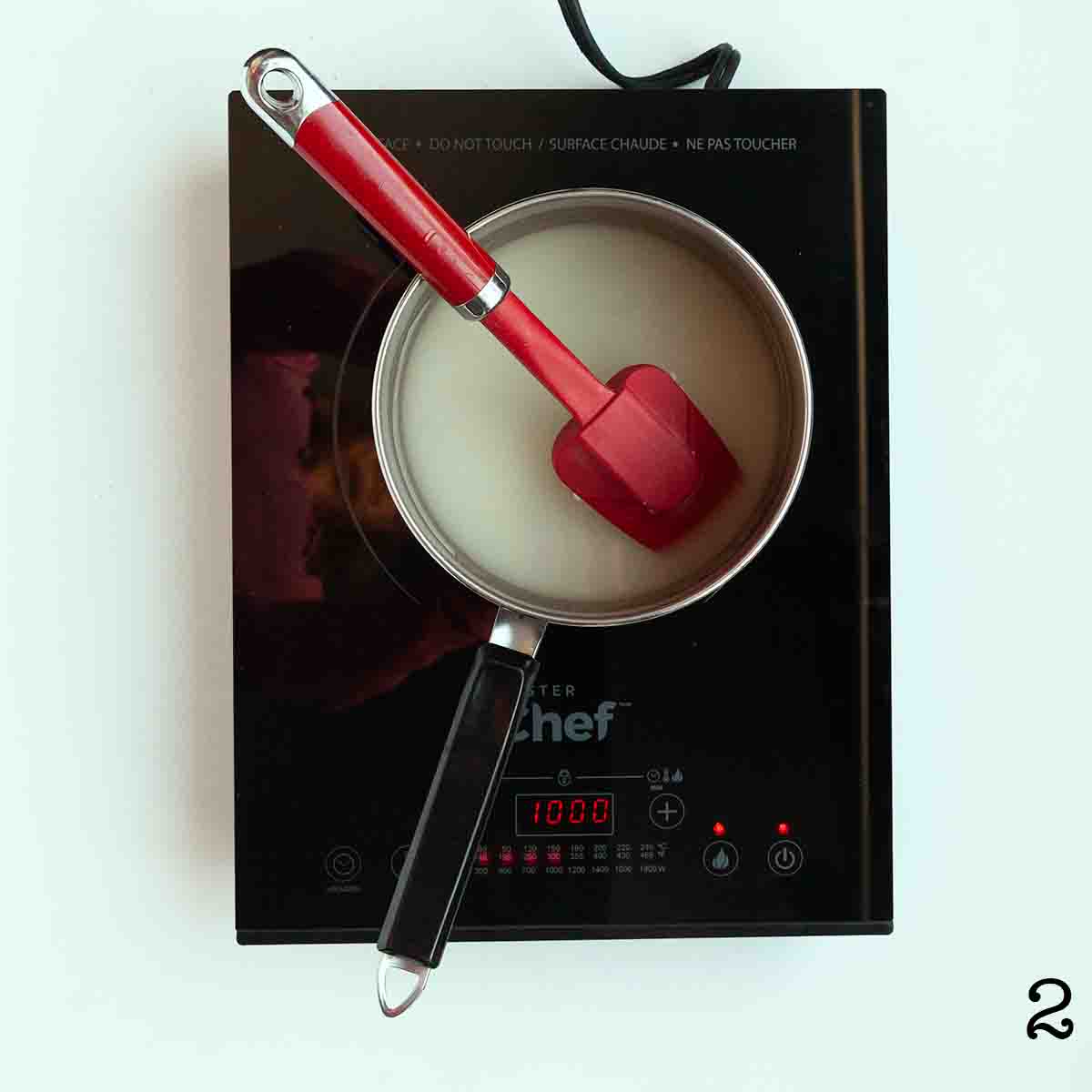 A saucepan with sugar and water on an induction burner.
