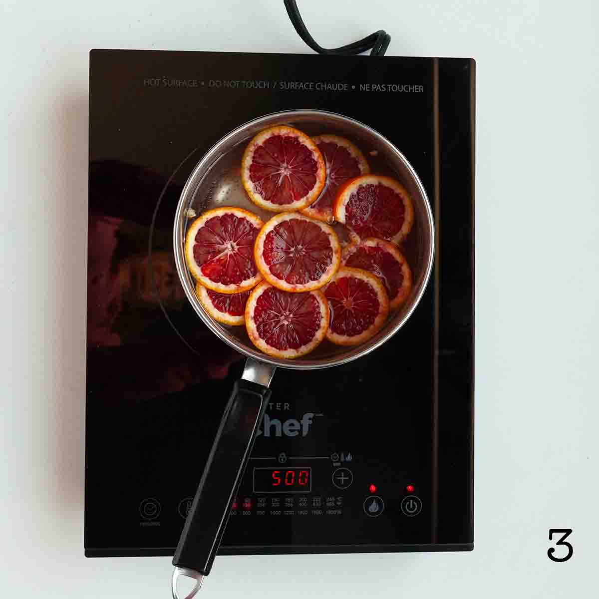 Blood orange slices simmering in syrup.