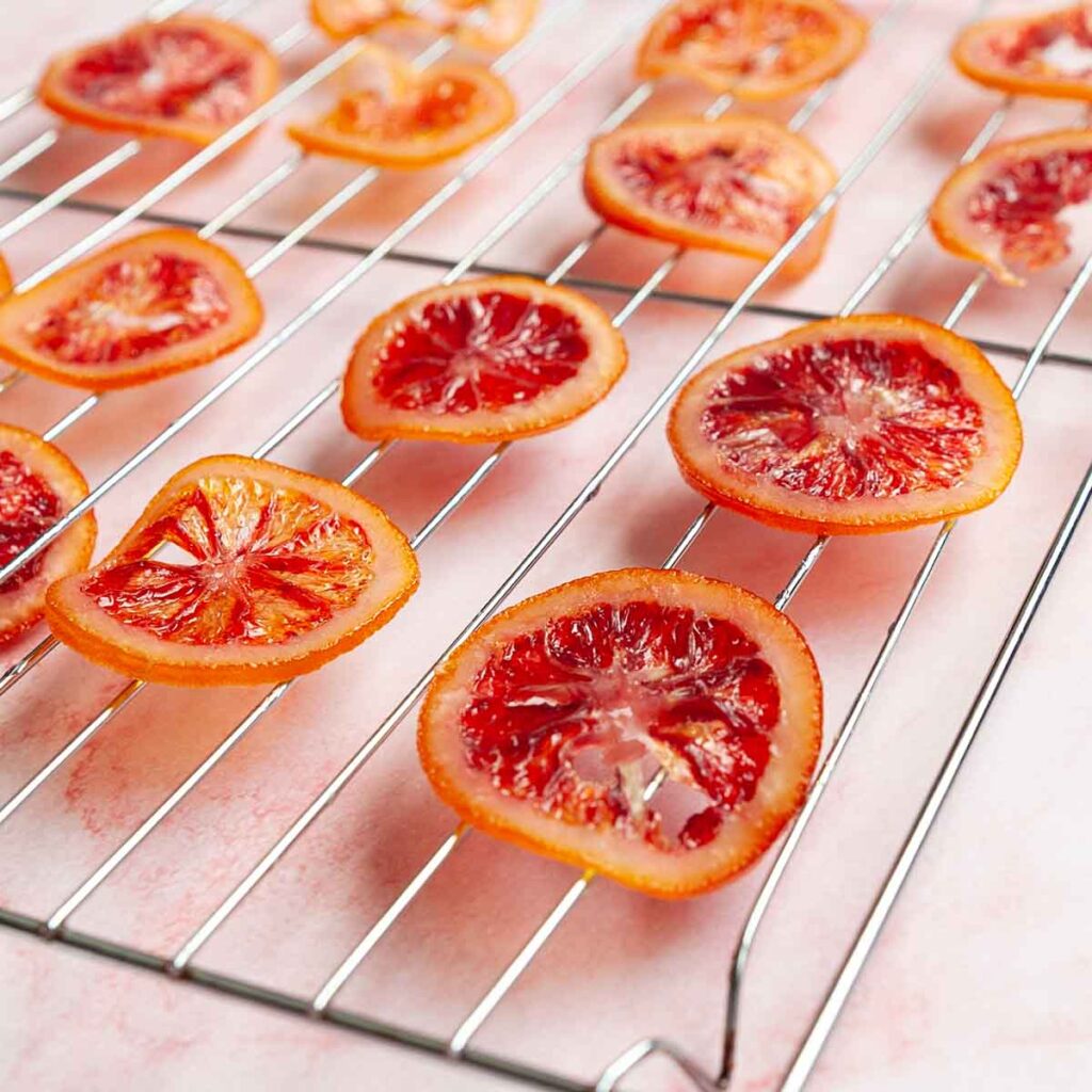 Slices of candied blood orange on a wire rack.