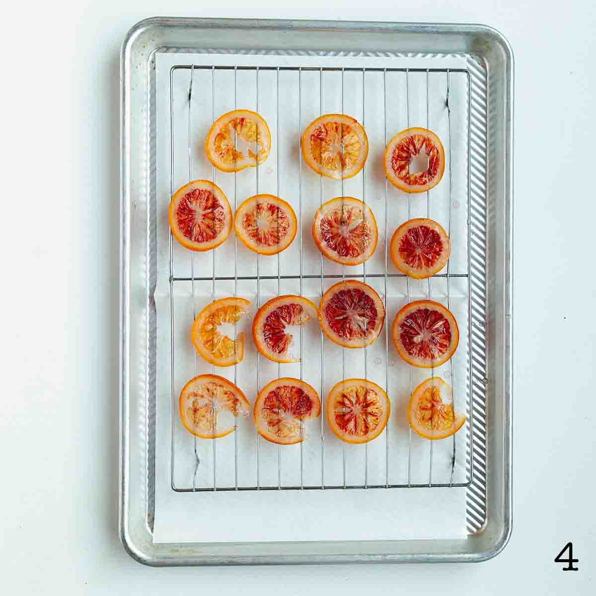 Slices of candied blood orange drying on a wire rack.
