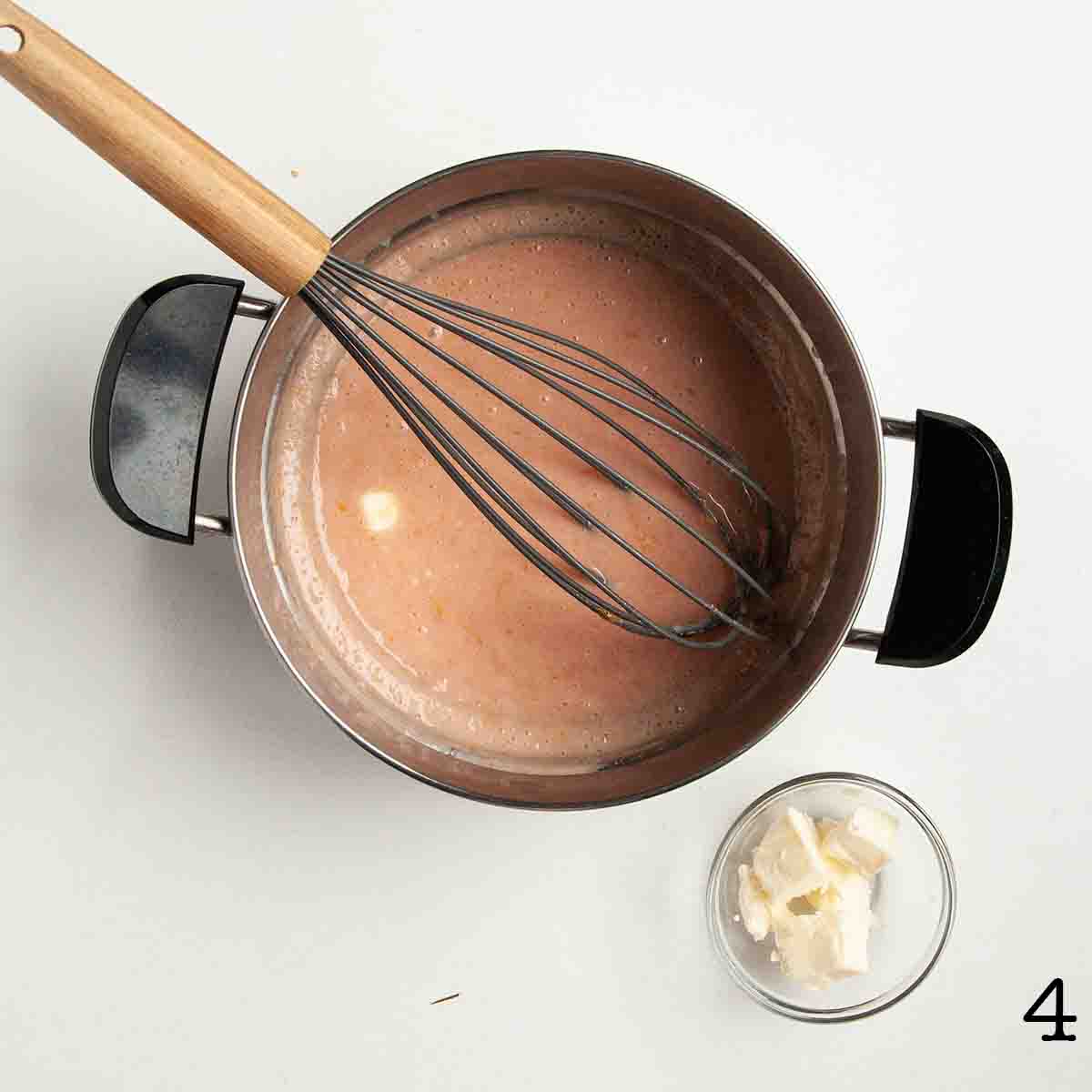 Butter being whisked into orange curd.