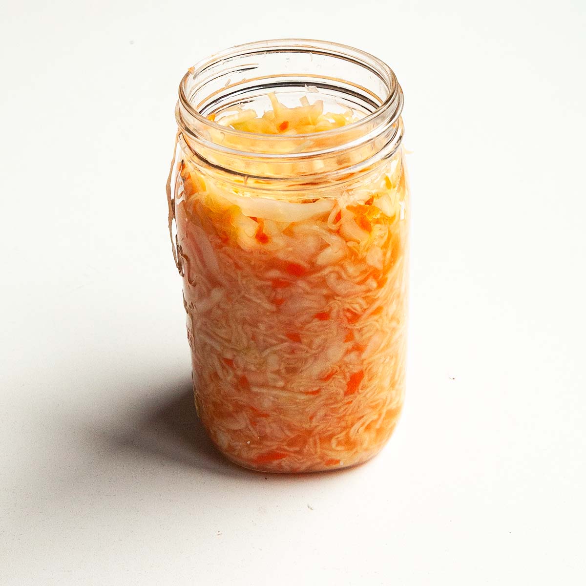 A jar of sauerkraut with carrots.