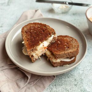 A halved grilled cheese sandwich with sauerkraut on a plate.