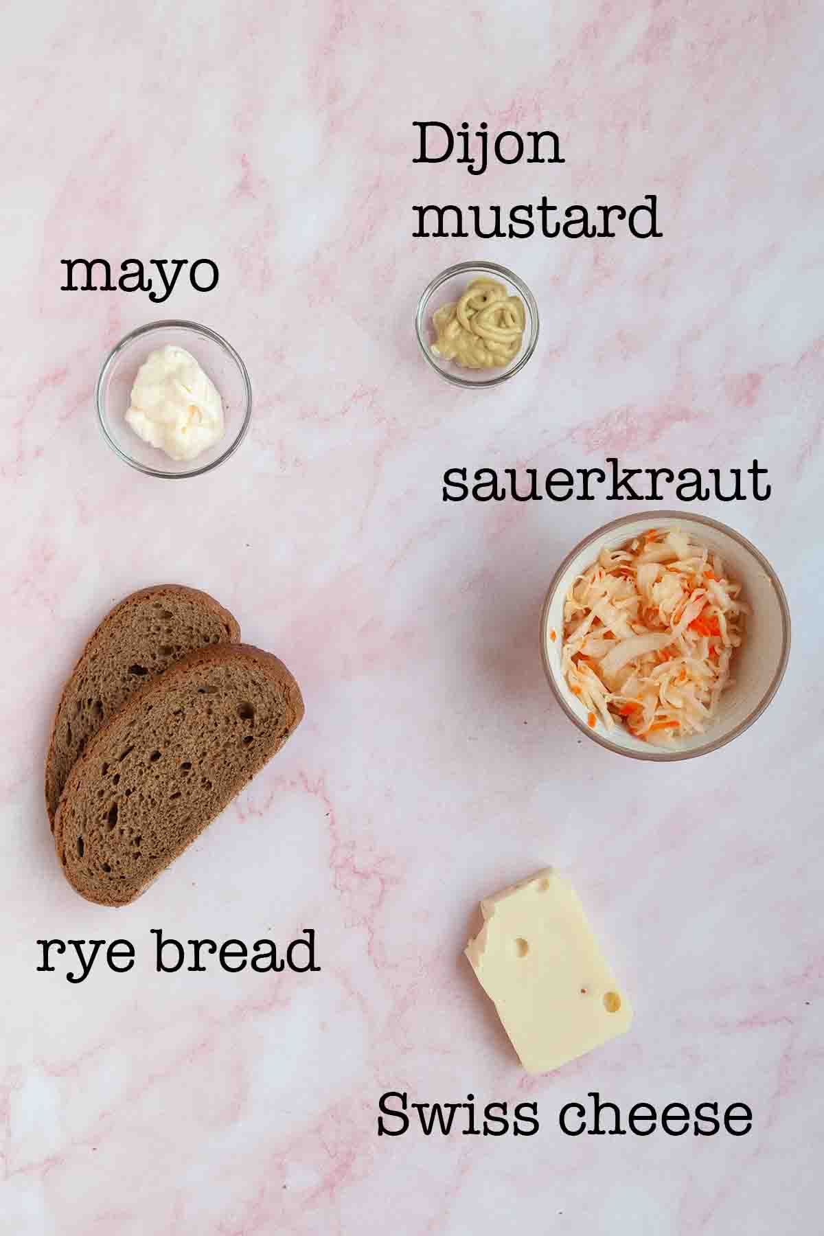 Ingredients for sauerkraut grilled cheese--mayo, Dijon mustard, rye bread, sauerkraut, and Swiss cheese.