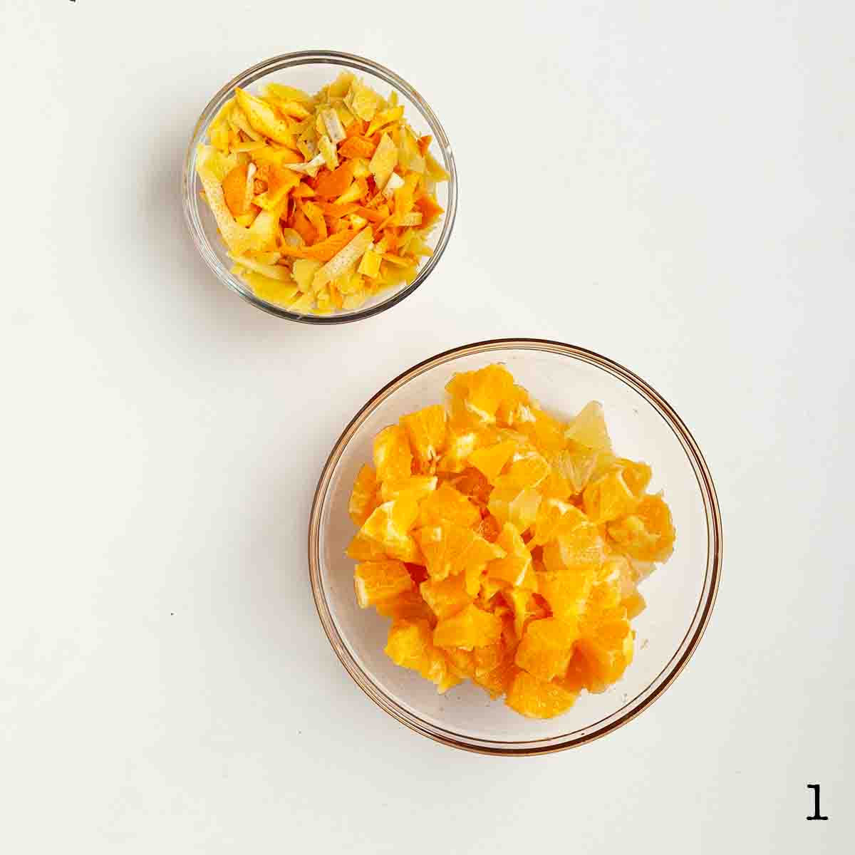 A dish of chopped orange and lemon zest and a bowl of chopped fruit.