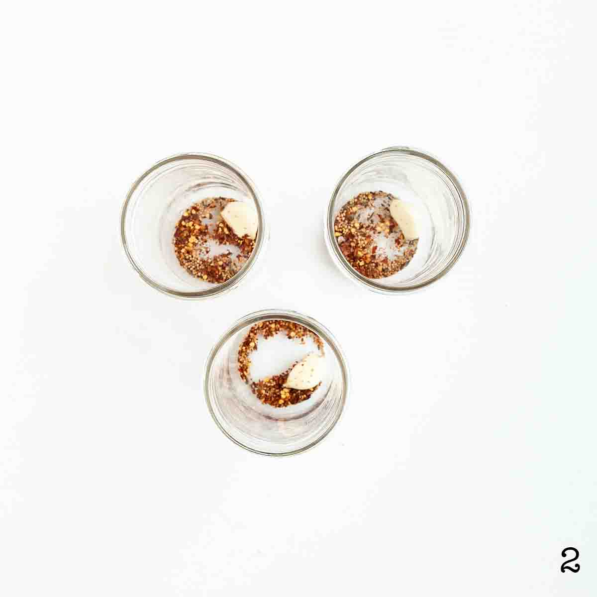 Three jars with spices and garlic in them.