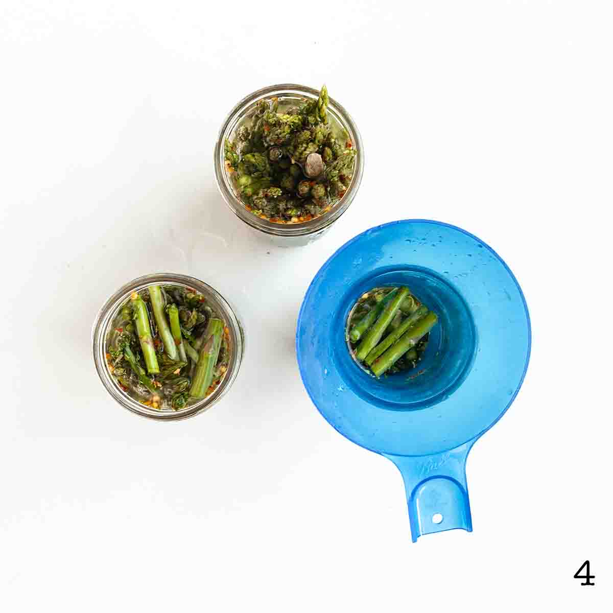 Brine being poured into jars of asparagus for pickling.