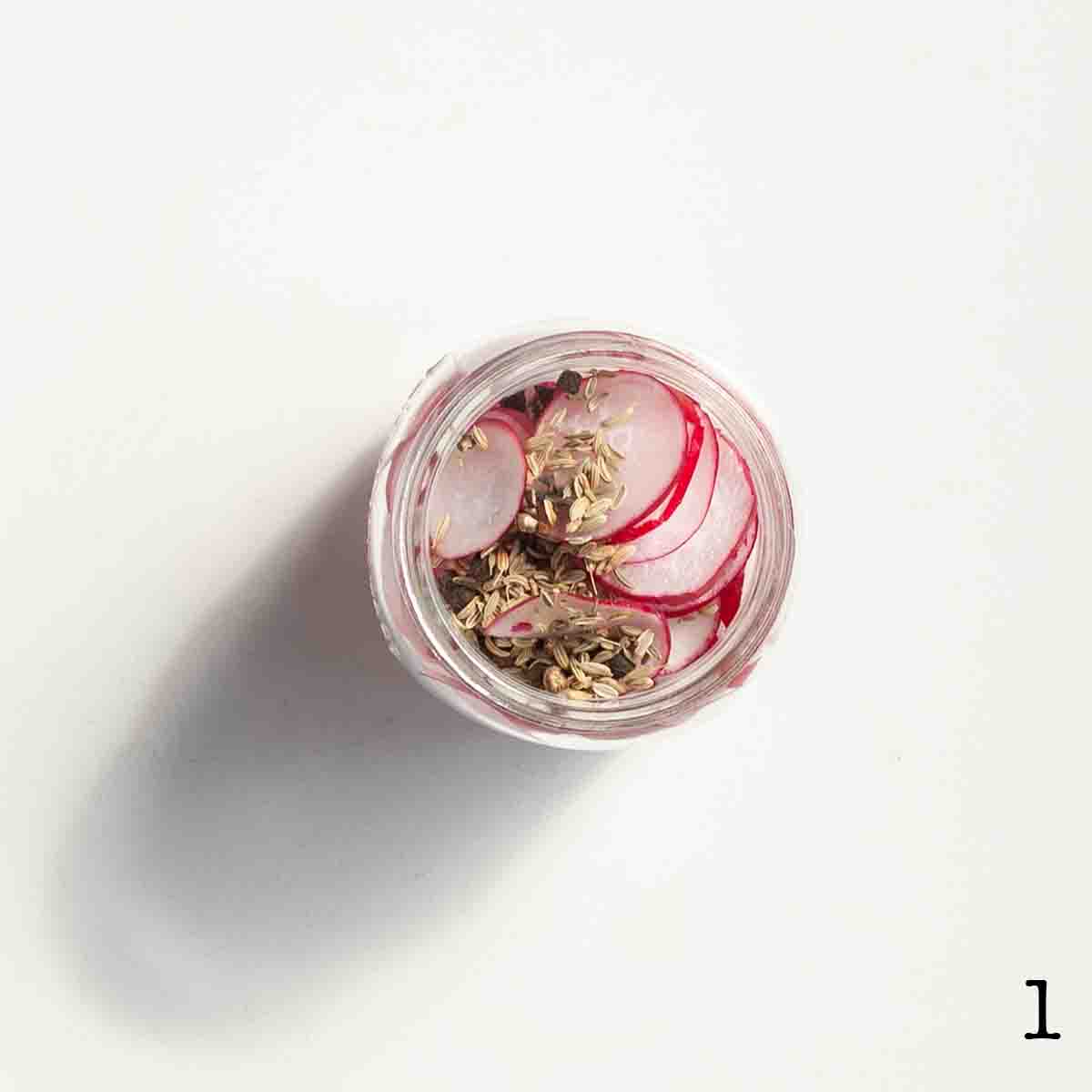 A jar filled with sliced radish and spices.