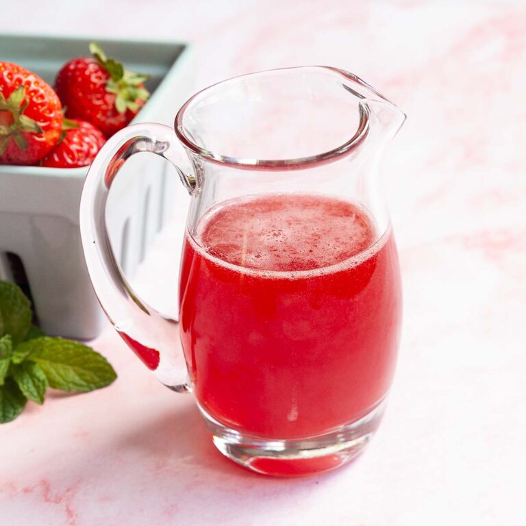 A small pitcher of strawberry syrup.