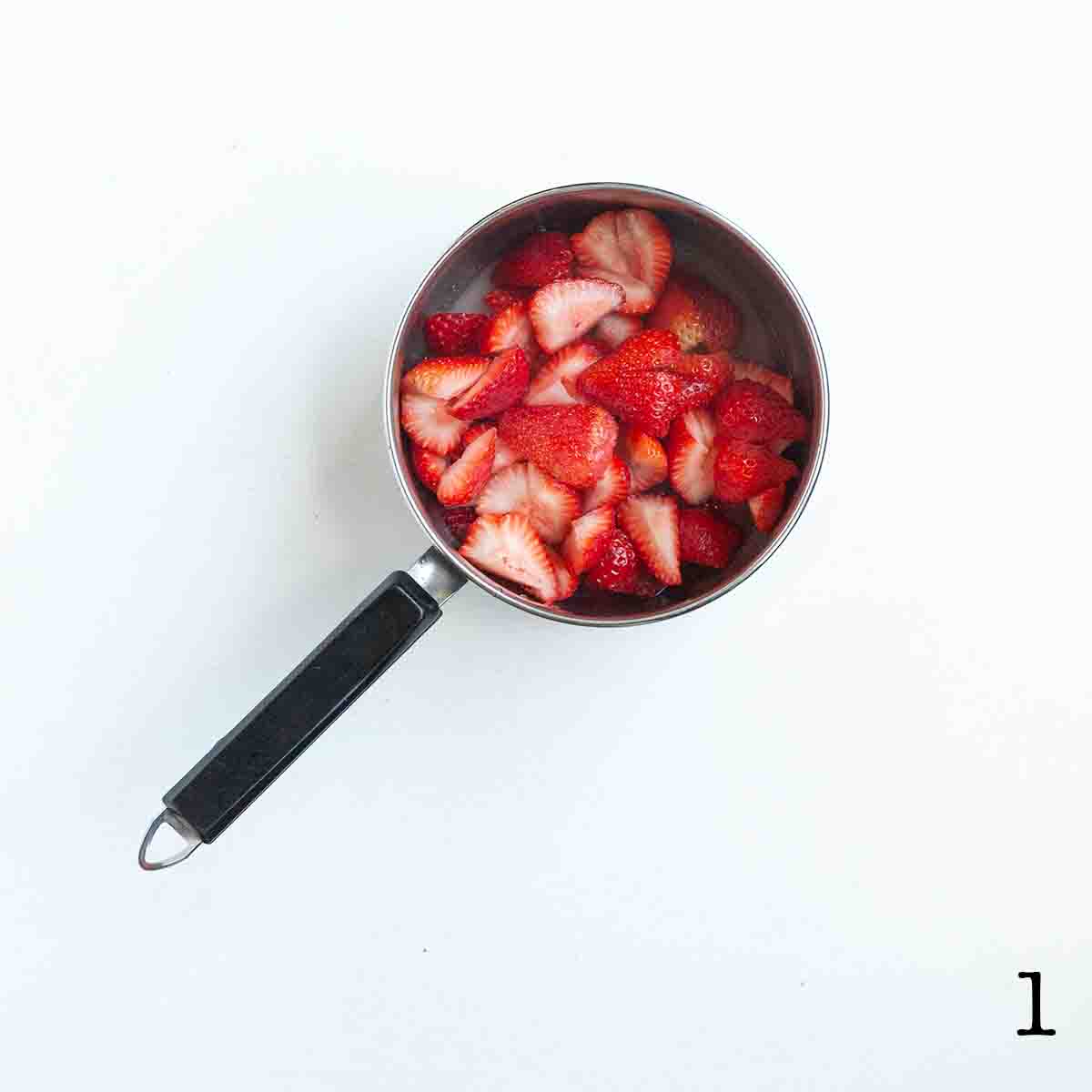A saucepan filled with strawberries and sugar.
