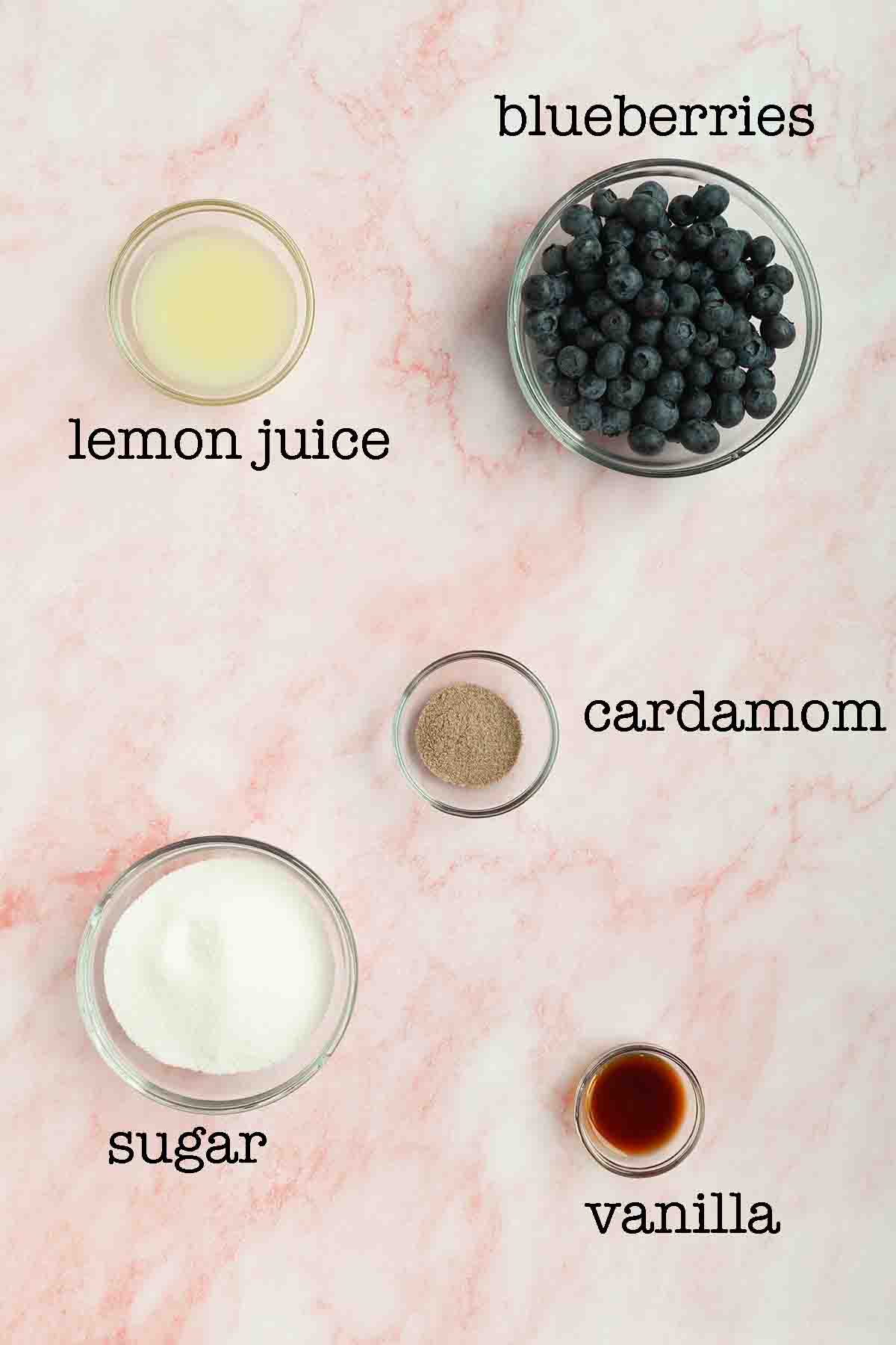 Ingredients for blueberry vanilla jam--lemon juice, blueberries, sugar, cardamom, and vanilla.