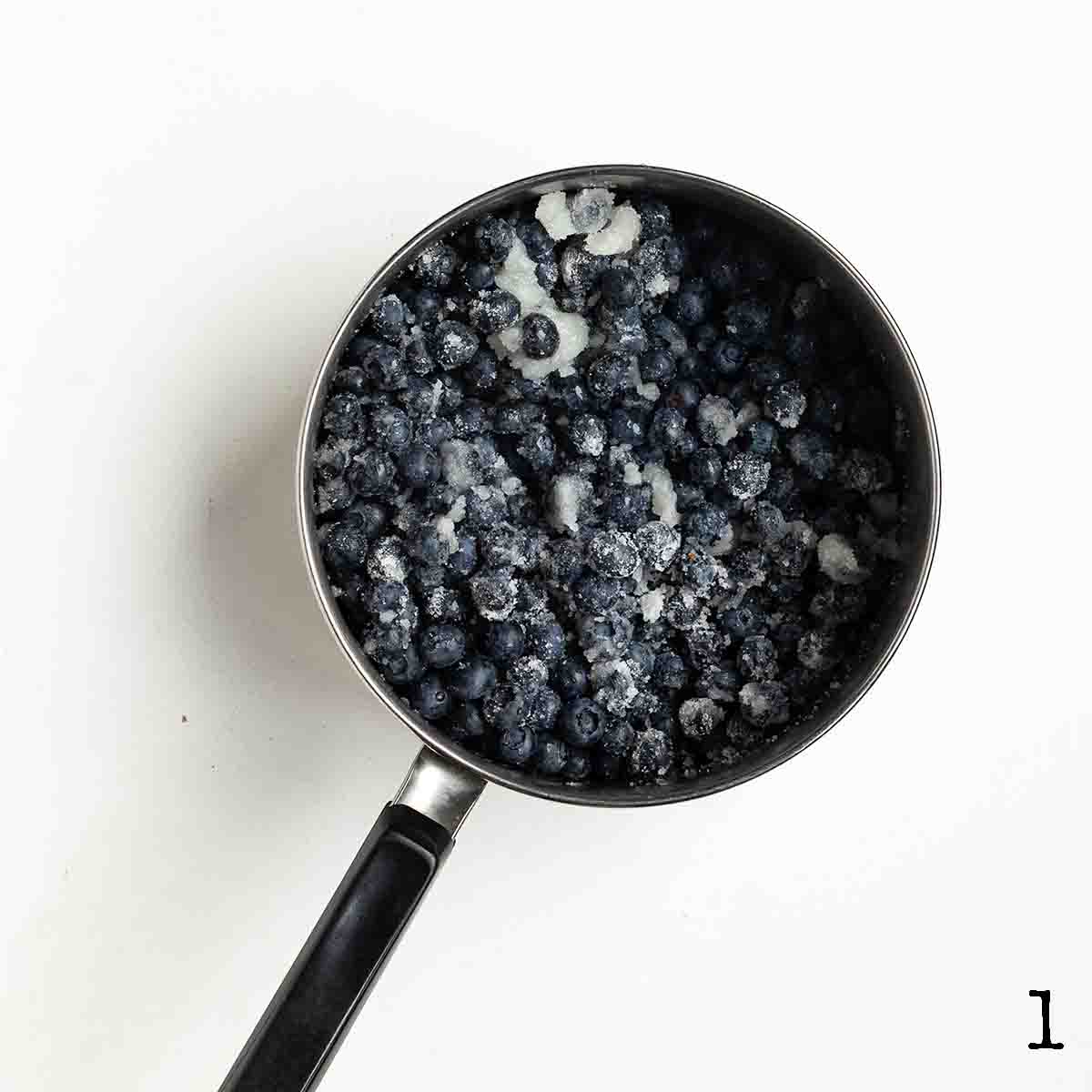 Blueberries and sugar in a pot.