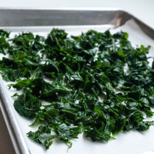 Blanched pieces of kale on a baking sheet.