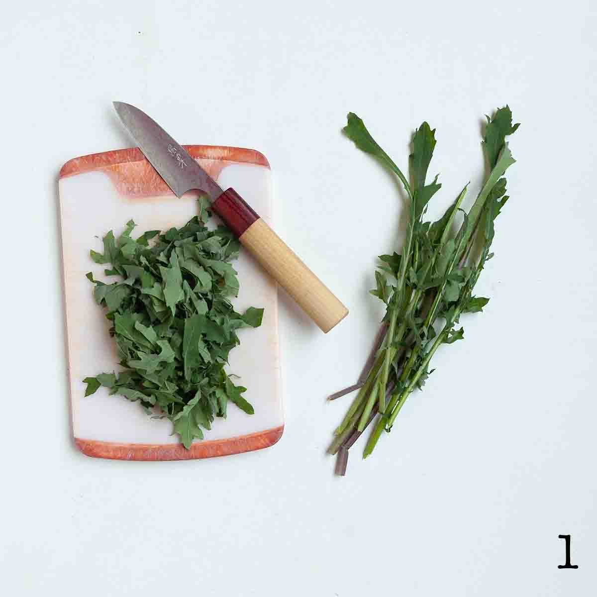 Pieces of chopped kale on a cutting board with the stems nearby.