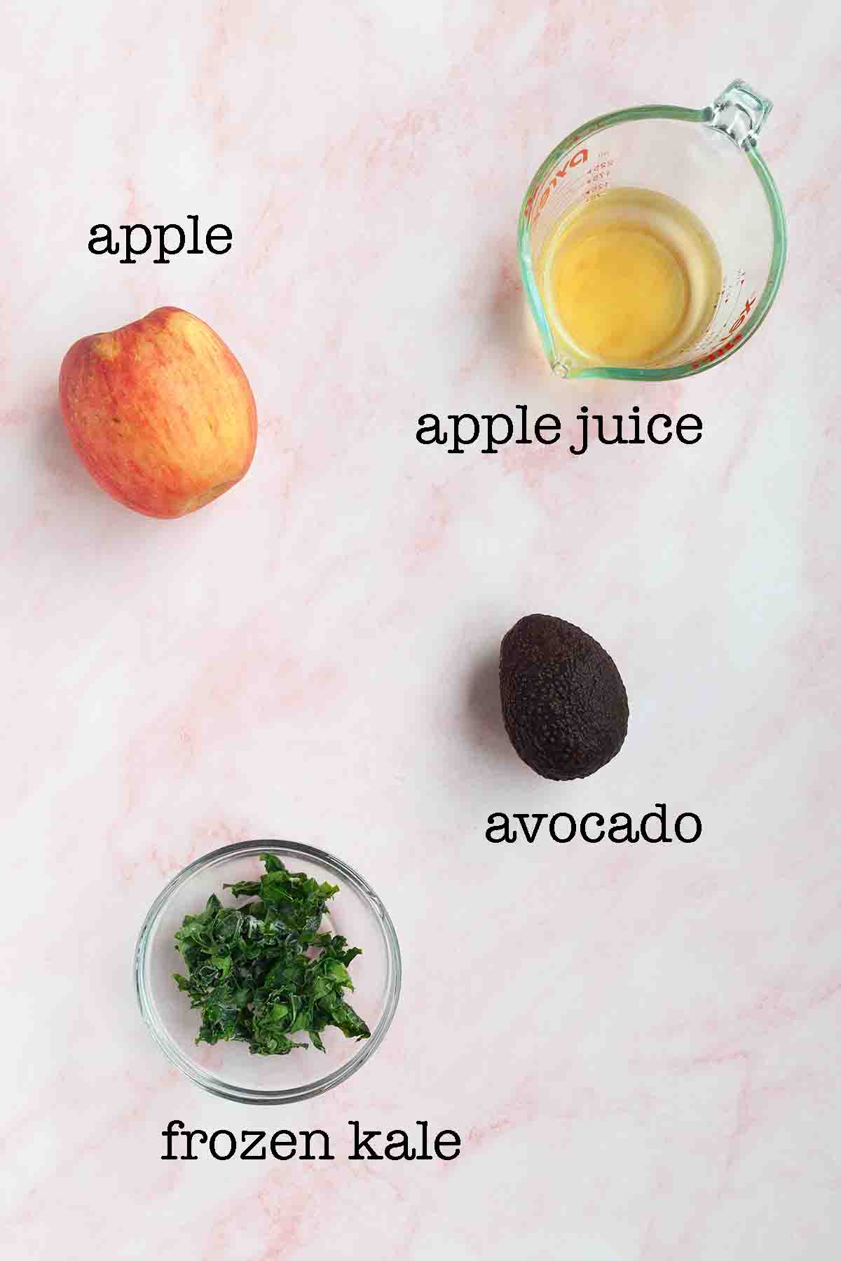 Ingredients for a kale avocado smoothie--apple, apple juice, avocado, and frozen kale.