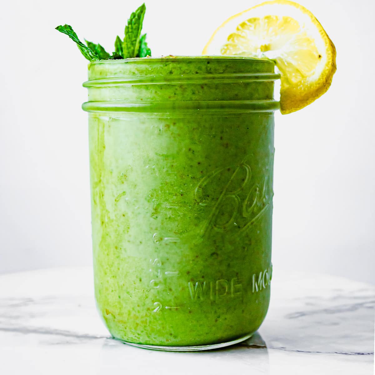 A green smoothie in a jar with a slice of lemon.