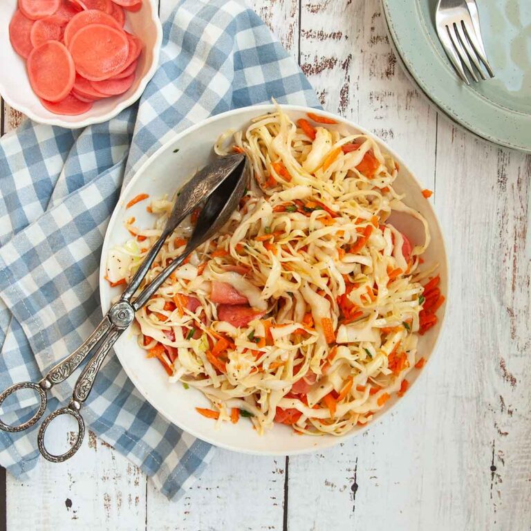 A bowl of coleslaw with cabbage, carrots, and pickled radish.