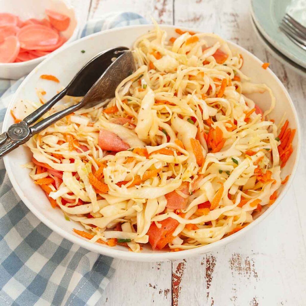 A bowl of coleslaw with cabbage, carrots, and pickled radish.
