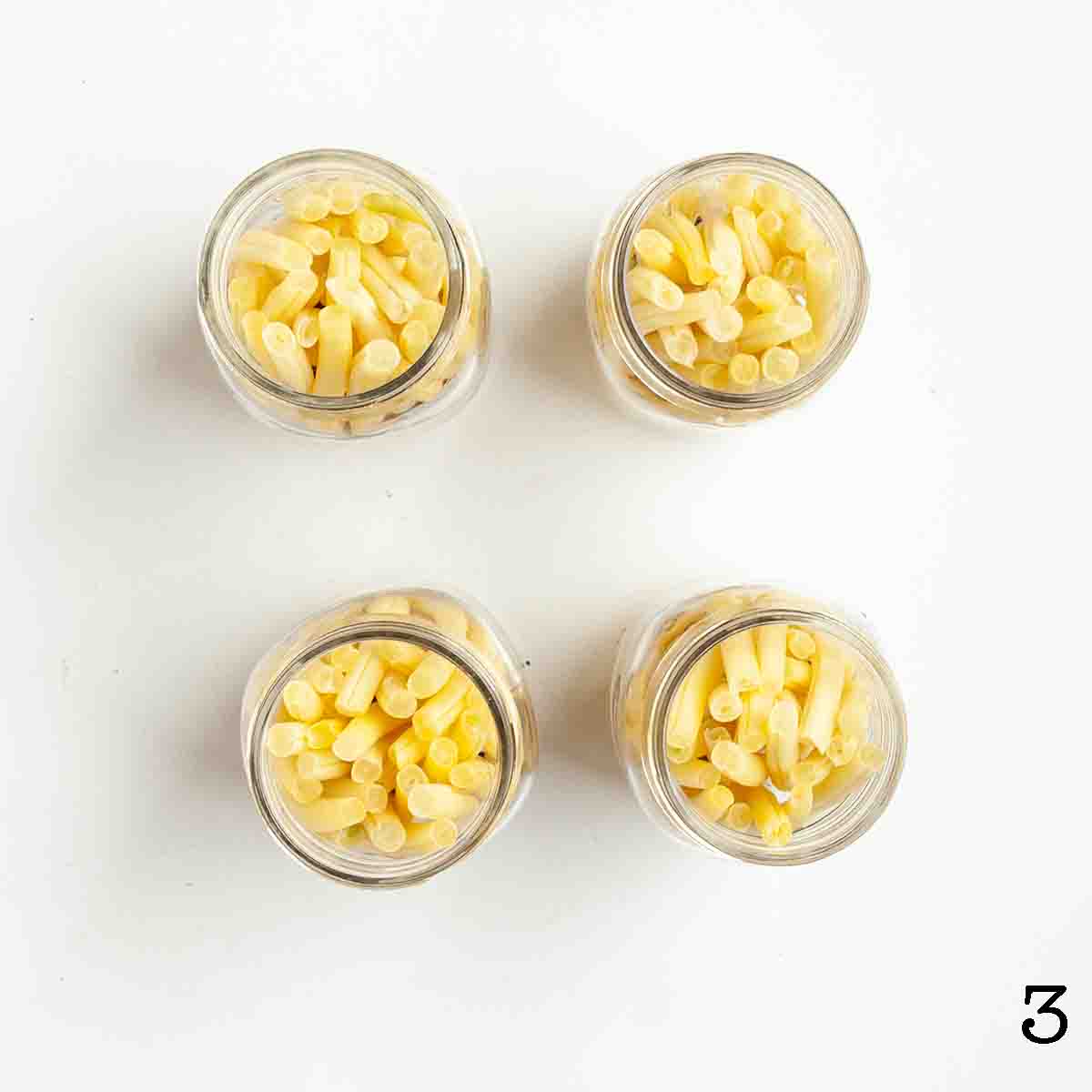 Four jars filled with raw yellow beans.