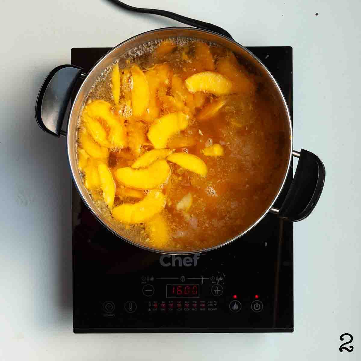 Sliced peaches boiling in a large pot.