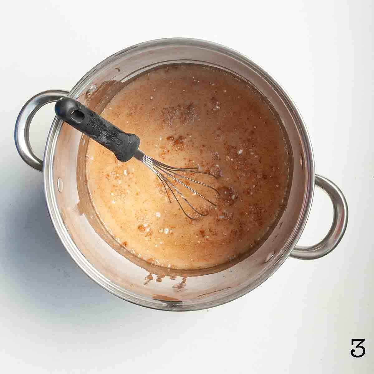 A slurry in a large pot with a whisk.