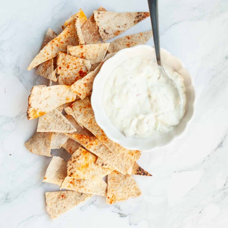 Homemade pita chips and a bowl of white dip.