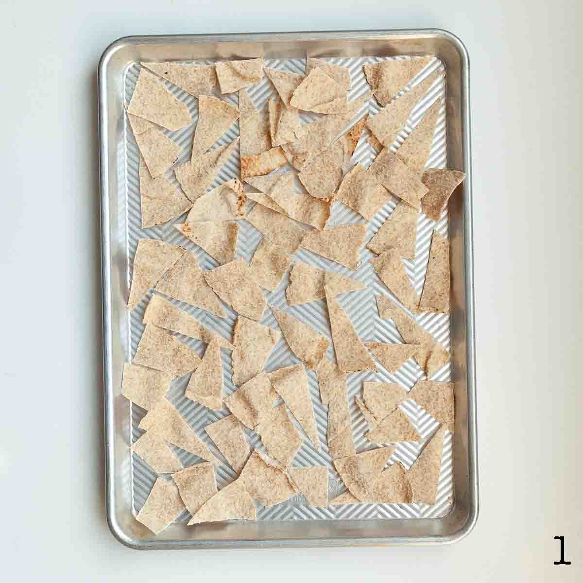 Pieces of pita bread cut into triangles on a baking sheet.