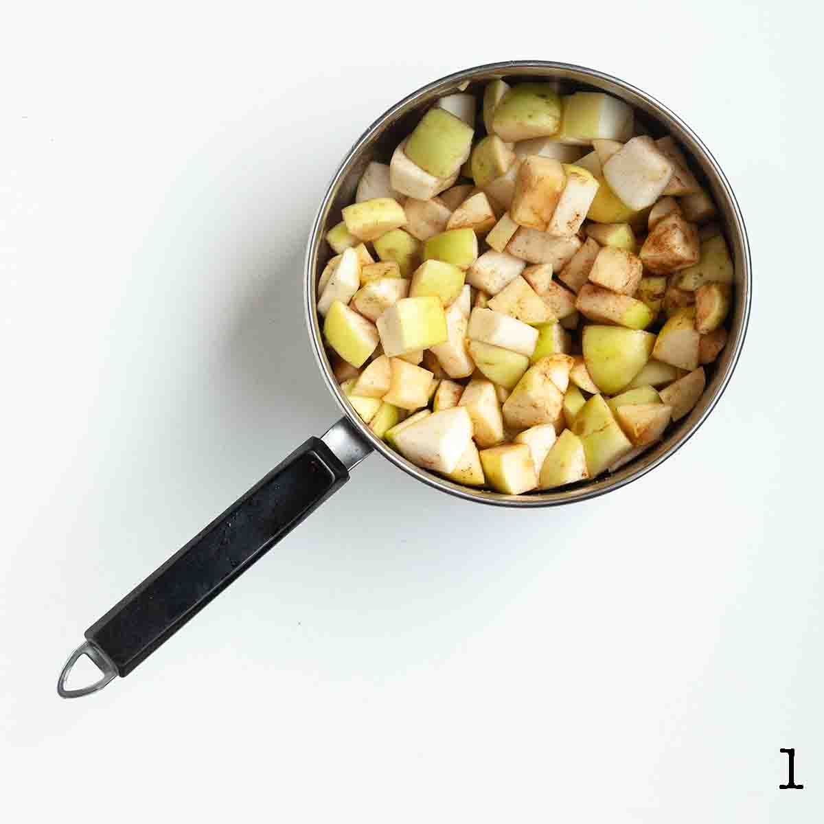 A pot with chopped apples and cinnamon inside.