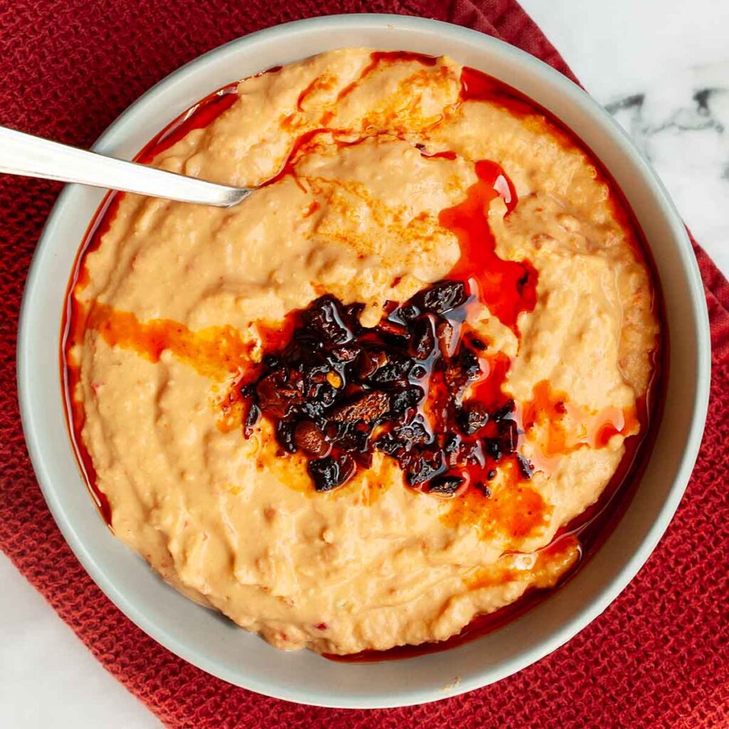 A bowl of roasted red pepper hummus topped with chili crisp.