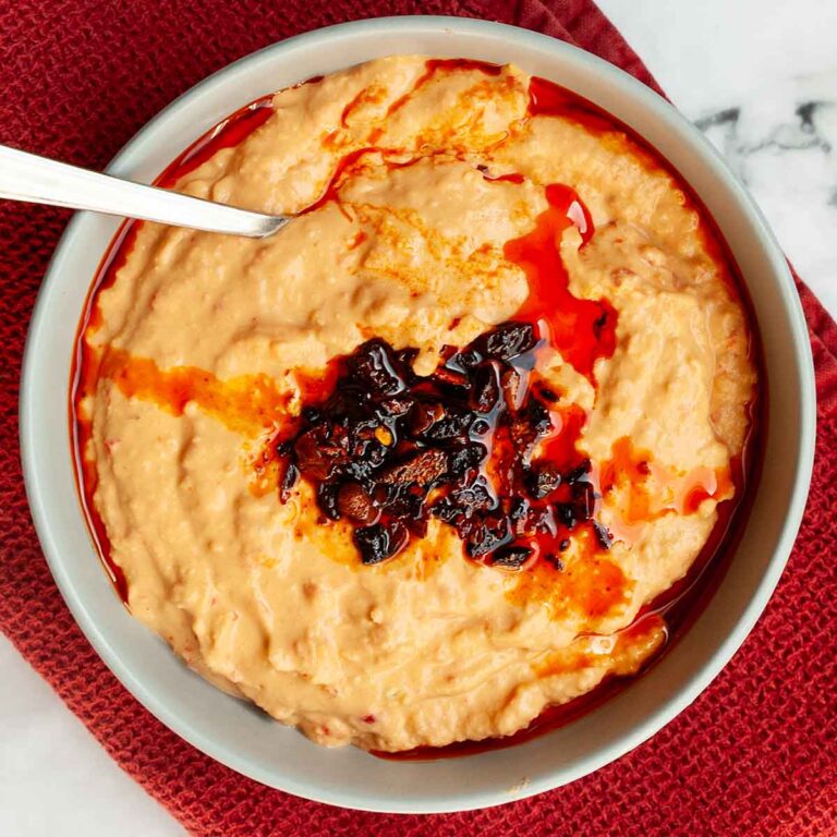 A bowl of roasted red pepper hummus topped with chili crisp.