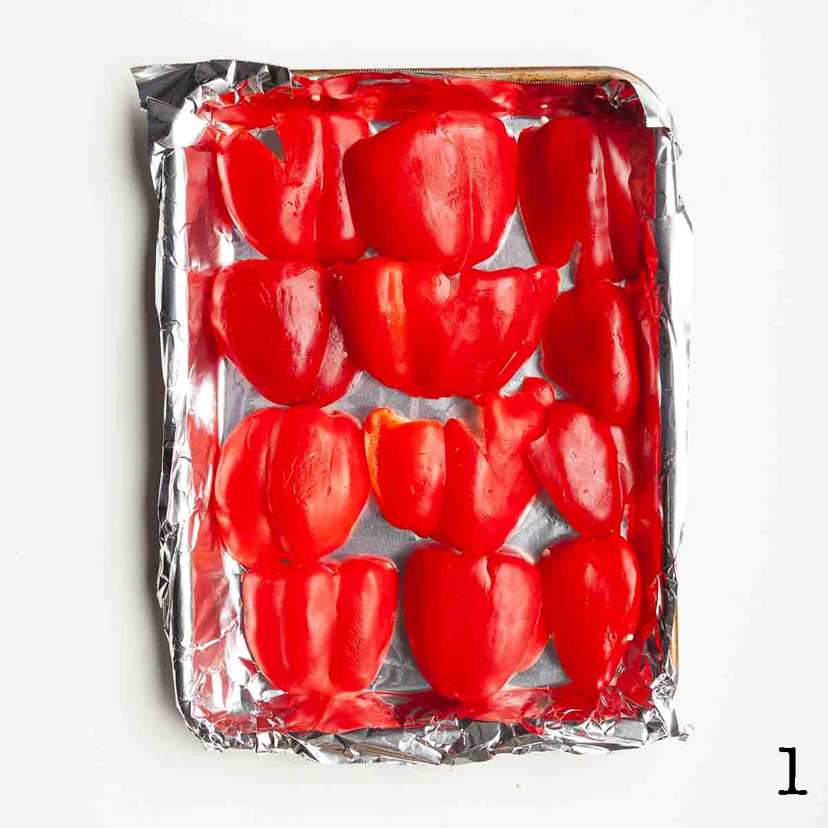 Halved bell peppers on a foil-lined baking sheet.